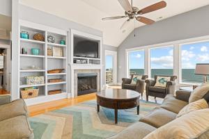 a living room with a fireplace and a ceiling fan at Cape Point Retreat 7 Bedroom Home by KEES Vacations in Buxton