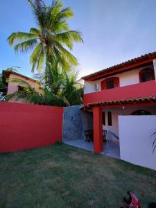 une maison rouge et blanche avec un palmier derrière elle dans l'établissement Casa na Praia de itacimirim Vila Maria, à Camassari