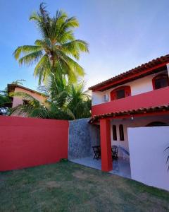 a house with a palm tree behind a fence at Casa na Praia de itacimirim Vila Maria in Camacari