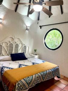 um quarto com uma cama, uma ventoinha de tecto e uma janela em Playa Car house em Playa del Carmen