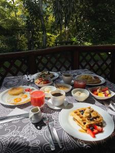 a table topped with plates of breakfast foods and drinks at Sacha Urco Lodge y Bosque Protector in Mindo