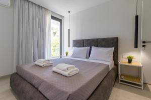 a bedroom with a large bed with towels on it at Varkiza Luxury Suites by Raise in Vari