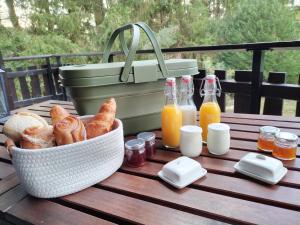 a picnic table with a basket of bread and bottles of juice at Chambre d'hôtes jacuzzi L'envol du coquelicot 
