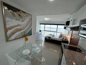 uma cozinha com uma mesa de vidro em frente a um quarto em Ecusuites Ejecutiva Mini view río guayas Aeropuerto em Guayaquil
