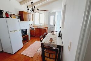 a kitchen with a table and a white refrigerator at Villa Kochili. in Symi