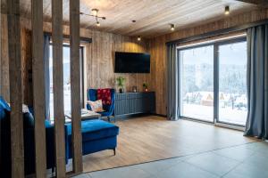 a living room with a blue couch and a tv at TATRZAŃSKIE TARASY Luxury Chalets in Małe Ciche