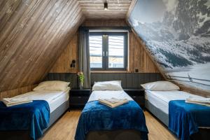 Habitación con 2 camas y una pintura en la pared. en TATRZAŃSKIE TARASY Luxury Chalets en Ciche Małe
