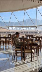 a man sitting at a table in a restaurant at Julia Rum Luxury Camp in Wadi Rum
