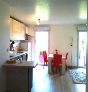 a kitchen with a table and red chairs in a room at Appartement calme rez-de-jardin in Saint-Étienne
