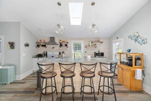 a kitchen with a counter with four bar stools at The Lyellton House: Water View, Steps from Beach in Colonial Beach