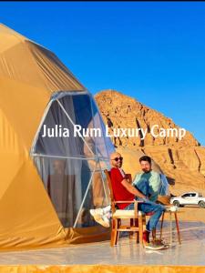two men sitting in front of a tent at Julia Rum Luxury Camp in Wadi Rum