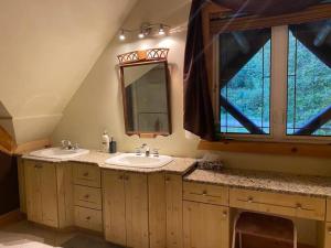 uma casa de banho com 2 lavatórios e uma grande janela em Lake side escape (log home) em Notre-Dame-de-la-Salette