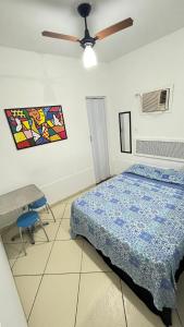 a bedroom with a bed and a table and a ceiling fan at Casa 4 hospedagem seropedica in Seropédica