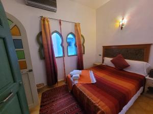 a bedroom with a bed and two windows at Honey Suckle in Chefchaouene