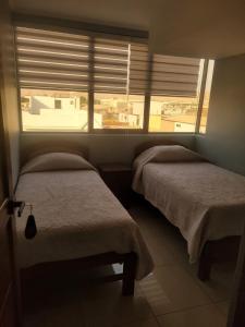 a bedroom with two beds and a window with blinds at Hostal Ostello Amadeus in Arica