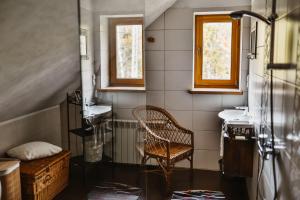 uma casa de banho com 2 lavatórios, uma cadeira e 2 janelas em Chałupa z widokiem w górach em Zawoja