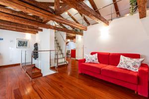 un sofá rojo en la sala de estar con suelo de madera en Glass House - Loft 2 minutes to Rialto Bridge & View, en Venecia