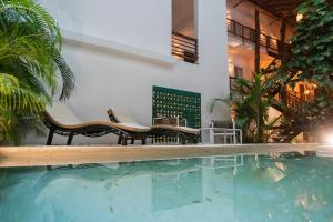 a swimming pool with two chairs and a house at Kanté Hotel - Downtown Tulum in Tulum