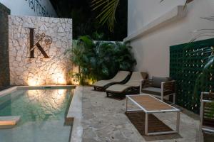a pool with chairs and a sign on a wall at Kanté Hotel - Downtown Tulum in Tulum
