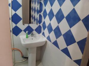 a bathroom with a sink and blue and white tiles at Chambre Orange in Mbour