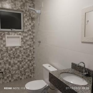 a bathroom with a toilet and a sink and a tv at Canto da Natureza in Governador Celso Ramos
