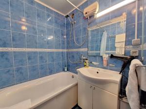 een blauw betegelde badkamer met een bad en een wastafel bij 4 ліжка з балконом Документи для відряджень Мережа Alex Apartments Безконтатне заселення 24-7 in Poltava