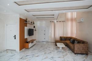 a living room with a brown couch and a tv at Elegant and Cosy Four Bedroom Home in Accra in Accra