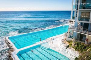 een uitzicht over een zwembad naast de oceaan bij Bondi Beach House in Sydney