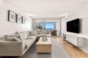 a white living room with a couch and a tv at Bondi Beach House in Sydney
