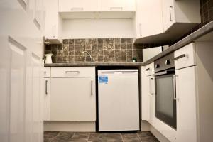 a kitchen with white cabinets and a refrigerator at The Stuart Suite - spacious, affordable, city centre in York +21 photos