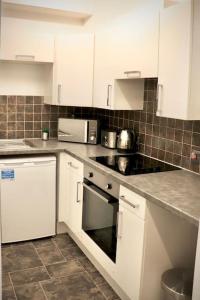 a kitchen with white cabinets and a stove top oven at The Stuart Suite - spacious, affordable, city centre in York