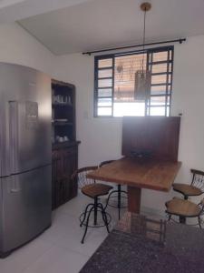 a kitchen with a wooden table and a refrigerator at Casinha Charmosa & Rústica in Indaiatuba