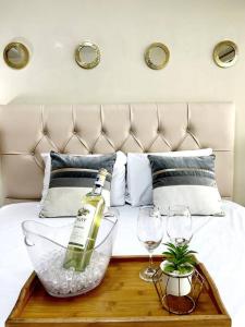 a bottle of wine and two glasses on a bed at Ecusuites Penthouse Torre Sol Aeropuerto Mall Del Sol in Guayaquil