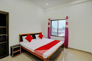 Un dormitorio con una cama con almohadas rojas y una ventana en OYO Flagship Hotel Bhardwaj en Varanasi