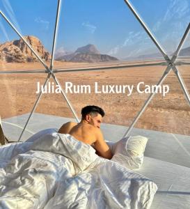 a man laying in bed in the desert at Julia Rum Luxury Camp in Wadi Rum
