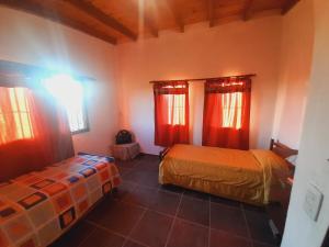 a bedroom with two beds and red curtains at Casa de la Montaña in Villa Parque Siquiman