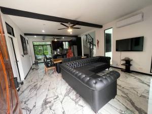 uma sala de estar com um sofá de couro e uma televisão em Rancho Hope em San Rafael Norte