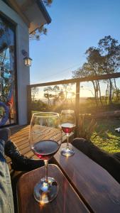 two glasses of wine sitting on a wooden table at Pousada Cabanas Araxá in Urubici