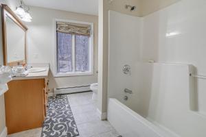 a bathroom with a tub and a sink and a toilet at Peaceful Cavendish Retreat with Hot Tub and Fireplace! in Proctorsville