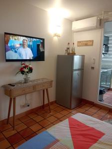 a room with a television and a table and a refrigerator at Studio MESANGE TARTANE in La Trinité