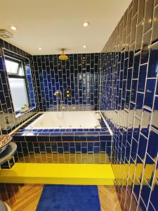 a bathroom with a tub with blue tiled walls at Jacuzzi Suite in London