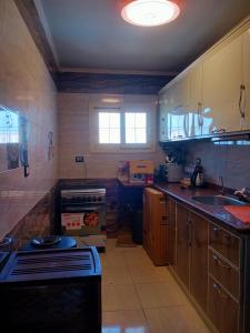 a kitchen with wooden cabinets and a sink and a stove at شقة فندقية بالإسكندرية بڤيو لا مثيل له in Alexandria