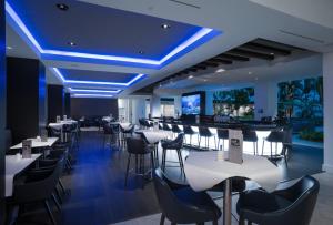 a restaurant with white tables and chairs and blue lighting at Innovation Hotel in Naples