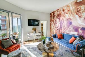 a living room with a blue couch and a painting on the wall at Luxe Long Beach Condo with Pool 1 Mi to Shoreline! in Long Beach