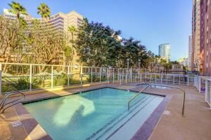 a swimming pool in a courtyard with trees and buildings at Luxe Long Beach Condo with Pool 1 Mi to Shoreline! in Long Beach