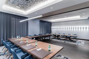 uma sala de conferências com mesas de madeira e cadeiras azuis em Innovation Hotel em Naples