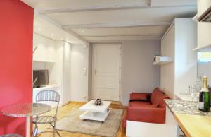 ein Wohnzimmer mit einem roten Sofa und einem Tisch in der Unterkunft Le Jardin du Village - Valbonne in Valbonne