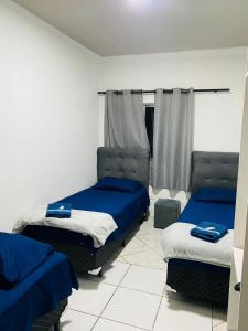 Habitación con 2 camas y sábanas azules. en HOSTEL ANPRADO, en Guarulhos