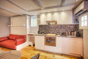 eine Küche mit weißen Schränken und einer roten Couch in der Unterkunft Le Jardin du Village - Valbonne in Valbonne