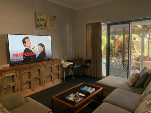 uma sala de estar com uma televisão de ecrã plano num centro de entretenimento em The Residence at MobyDick Resort em Yamba